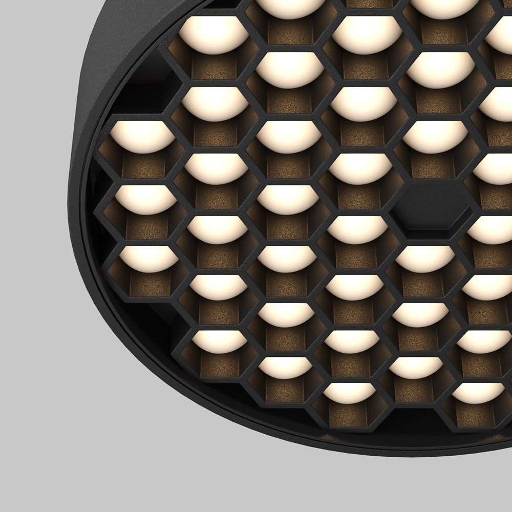 Détail rapproché de la grille alvéolée et des diodes en lumière chaude.