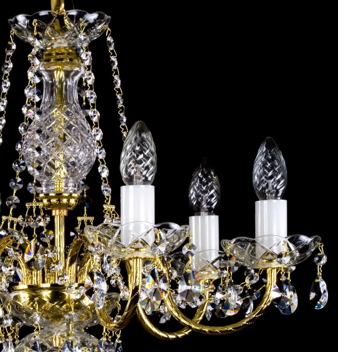 Détail de trois bras dorés, douilles blanches et bougies en verre taillé