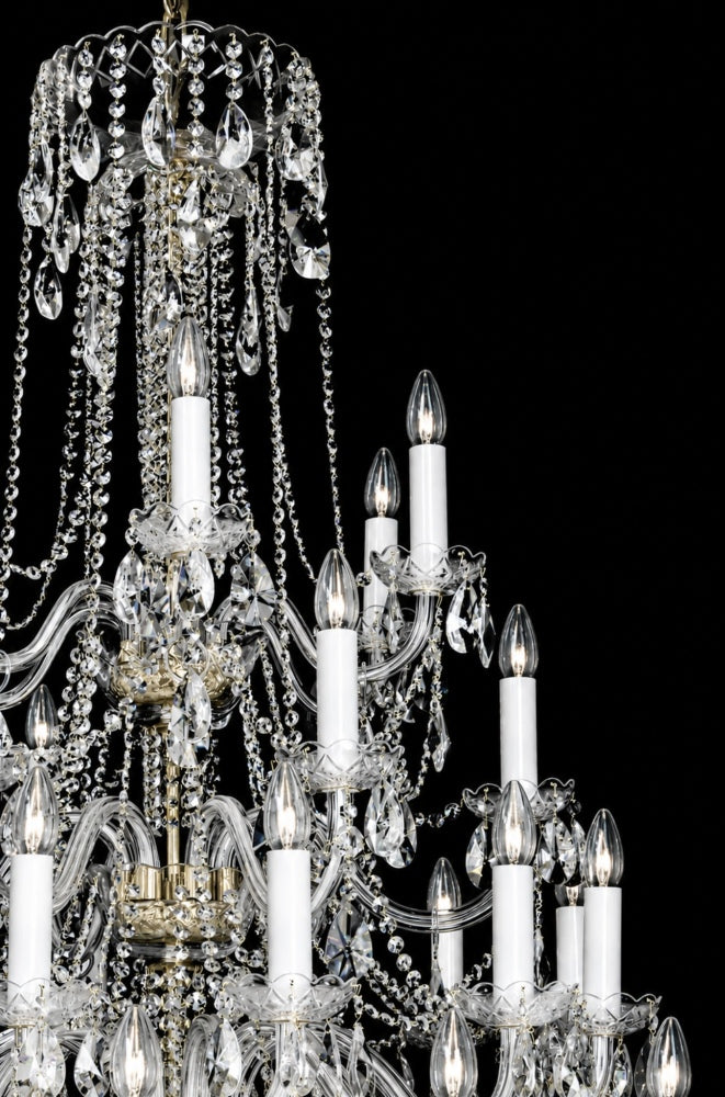 Gros plan sur les bras courbes en verre et les bougies blanches du lustre