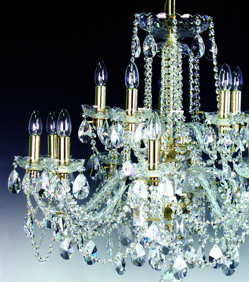Gros plan sur les bras dorés, pampilles et rosettes de cristal taillé du luminaire.