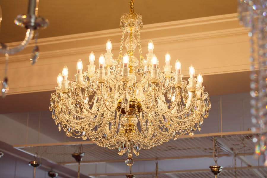 Vue en contre-plongée du lustre allumé dans un grand volume intérieur blanc.