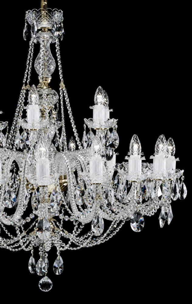 Gros plan sur les bras, bobèches et pendeloques de cristal taillé du luminaire.