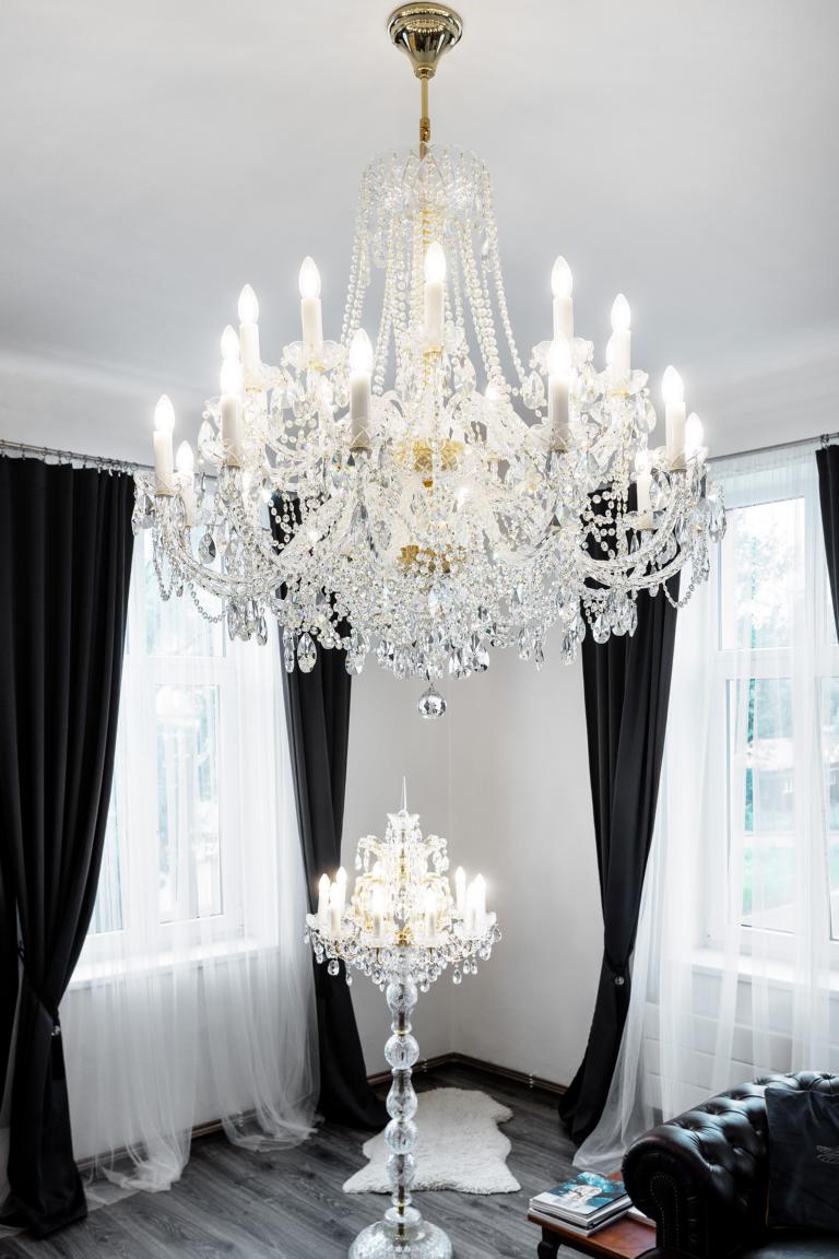 Vue verticale du lustre fixé au plafond, lampadaire identique en dessous, rideaux sombres.