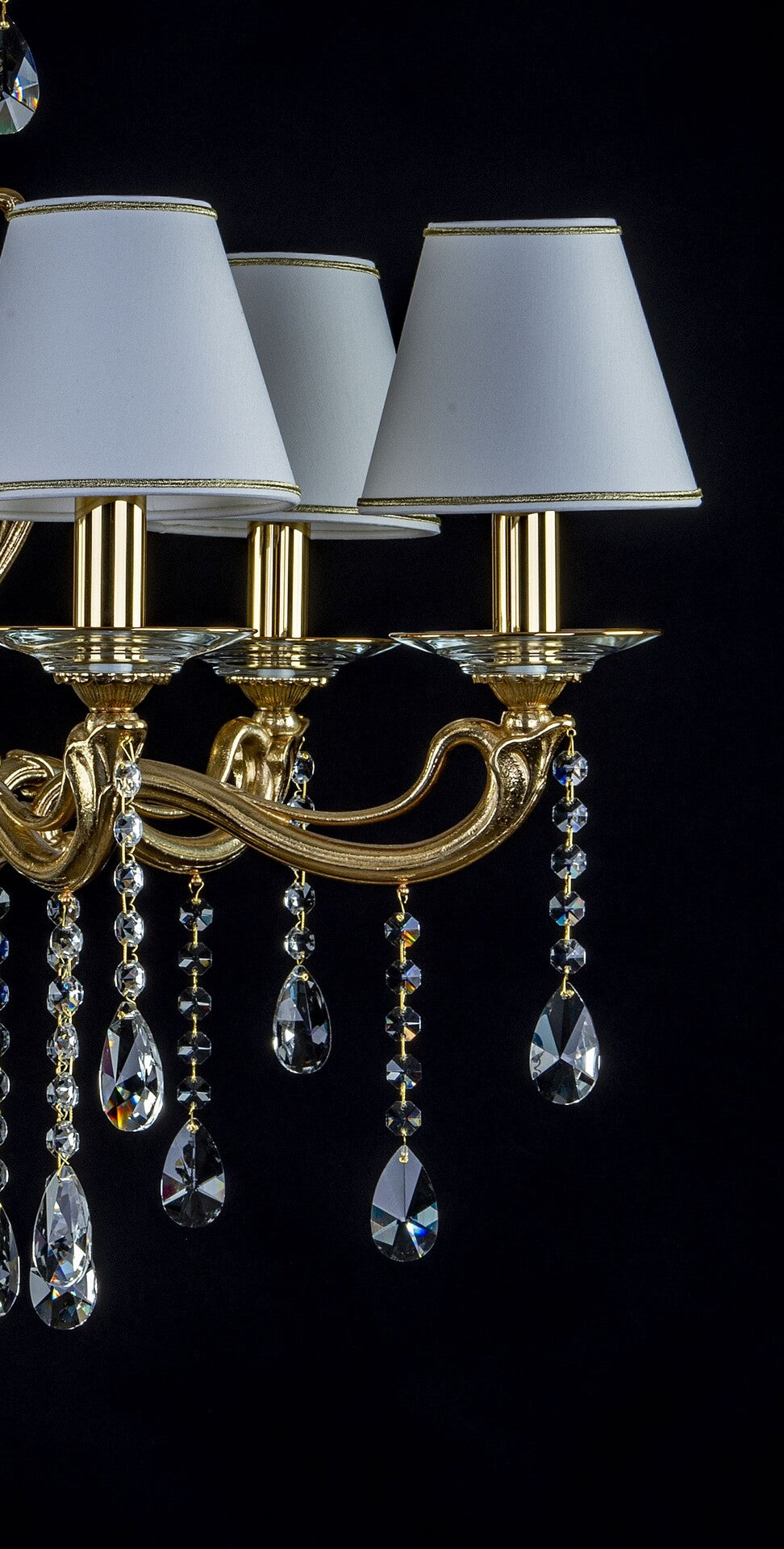 Détail rapproché des bras courbes en laiton, coupelles cristal et pendants gouttes taillées.