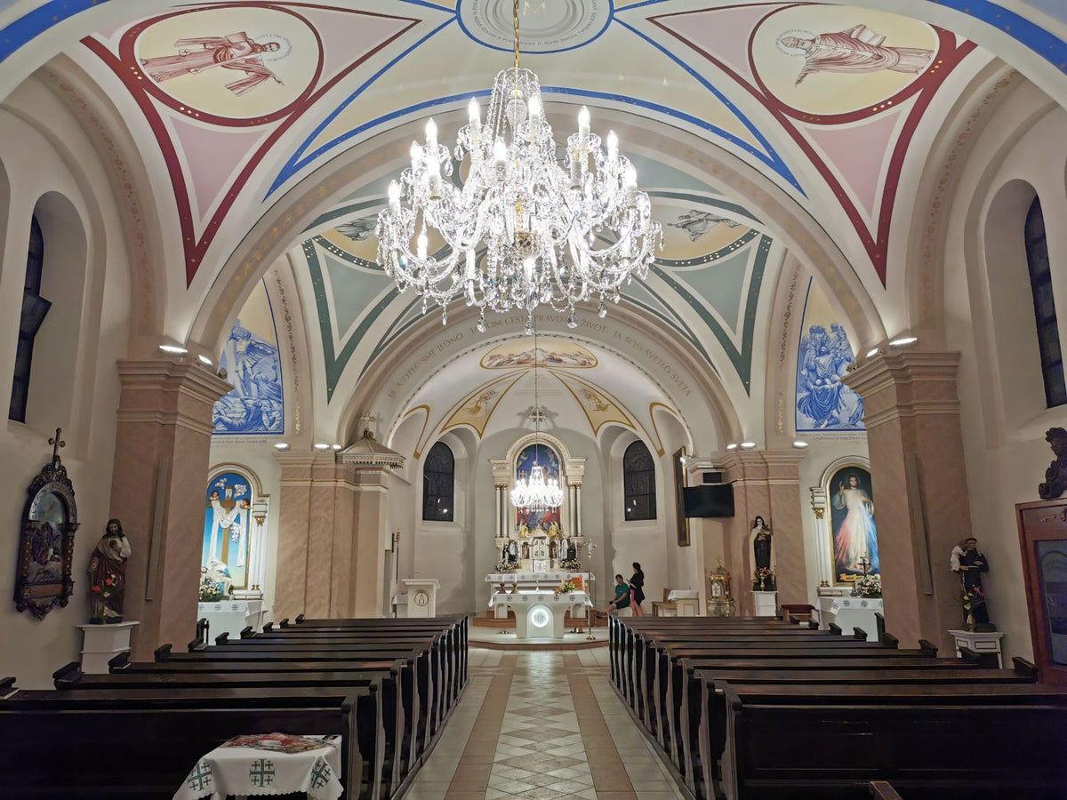 Lustre suspendu au plafond d'une église, au-dessus des bancs et de l'allée centrale.