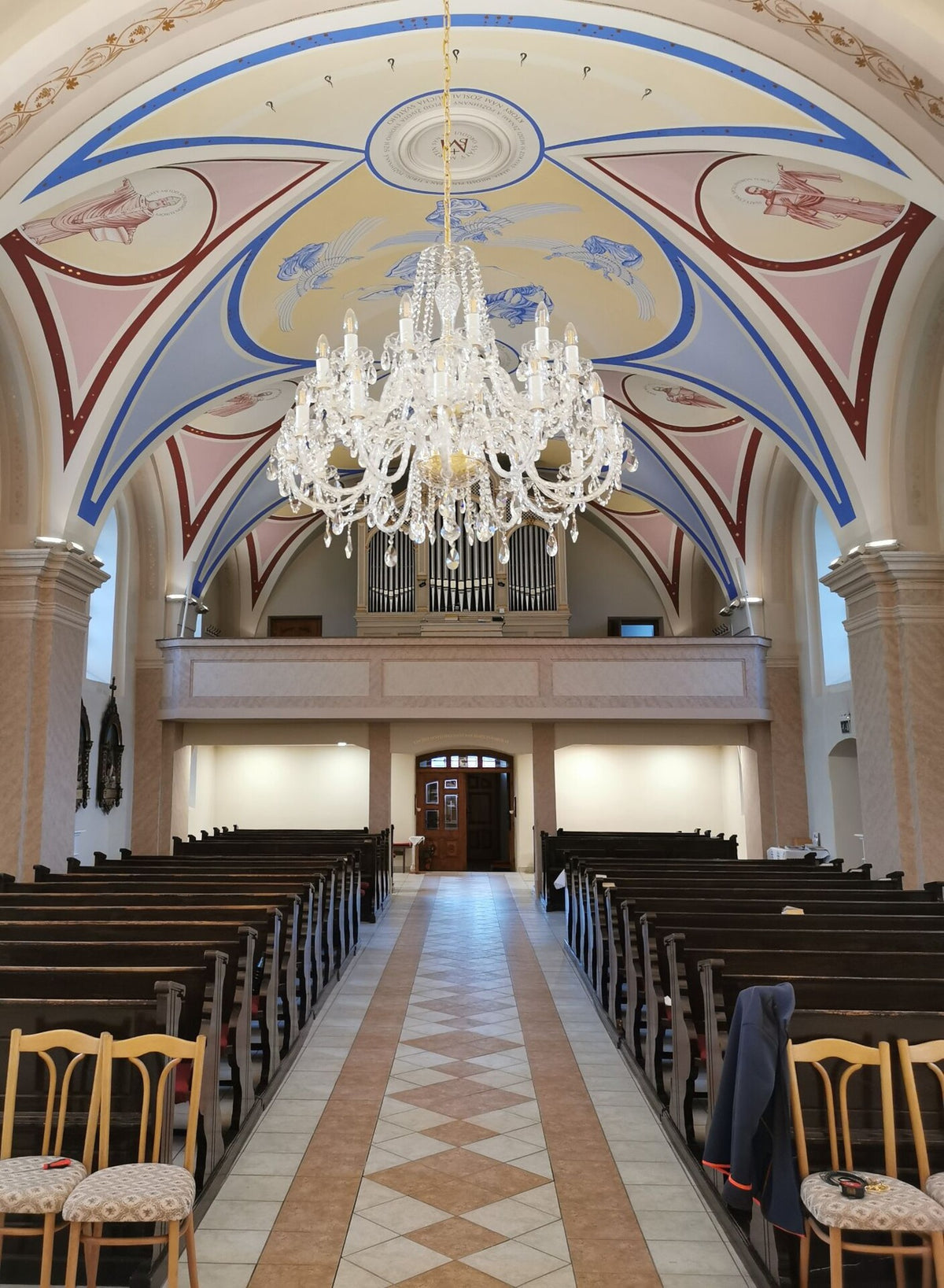 Vue plongeante depuis le fond de l'église, lustre en cristal devant l'orgue et la tribune.