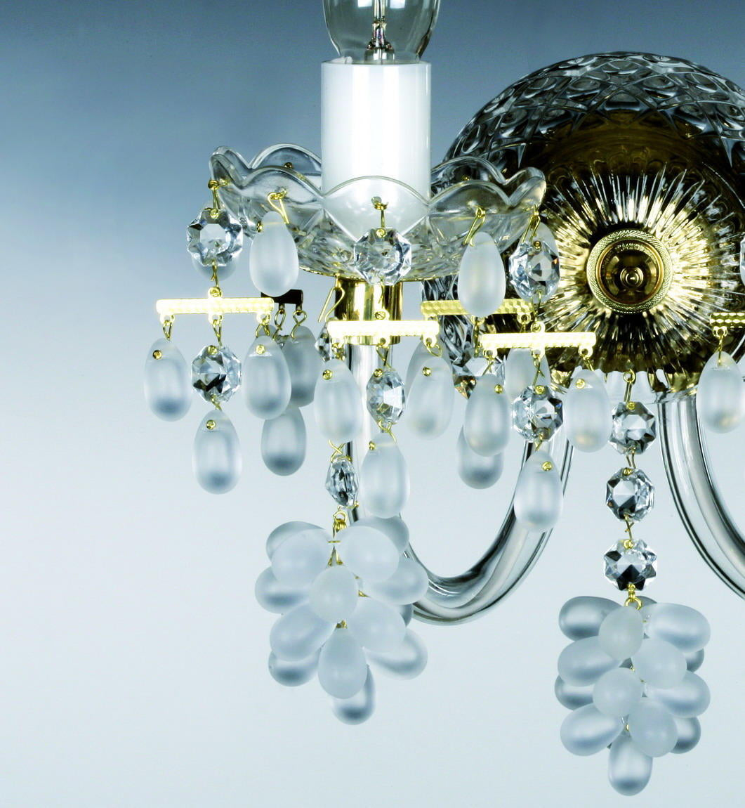 Gros plan sur les pendentifs en cristal taillé, grappes givrées et coupelle en verre festonnée du luminaire