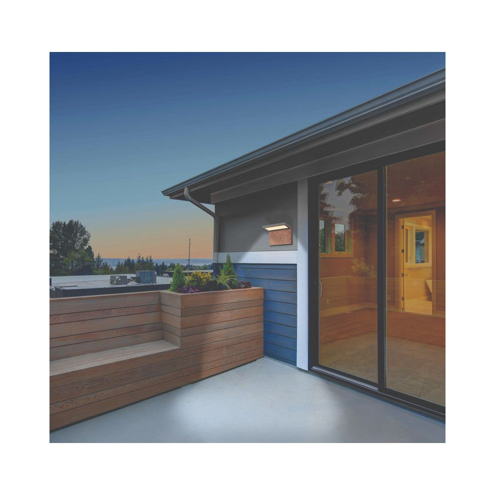 Mise en ambiance de l’applique murale éclairée sur une terrasse en bois au crépuscule.