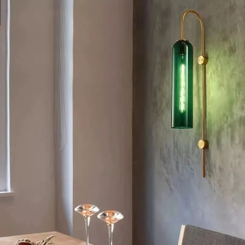 Applique murale en verre vert, bras doré recourbé, ampoule LED allumée sur mur gris