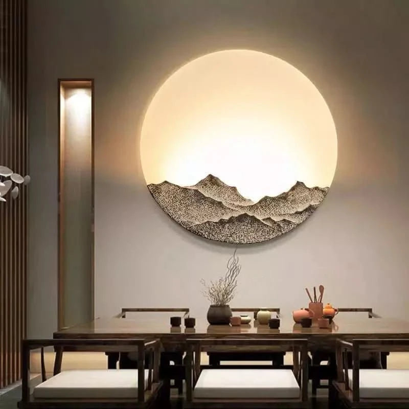 Applique ronde lumineuse éclairant une salle à manger en bois, relief de montagnes en bas