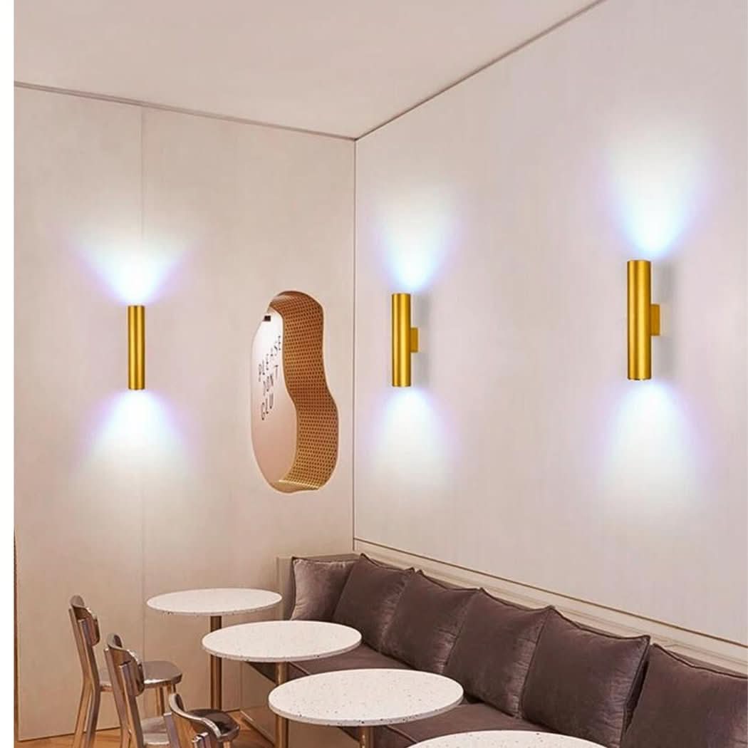 Appliques dorées au-dessus d'une banquette devant tables rondes, ambiance café lumineuse.
