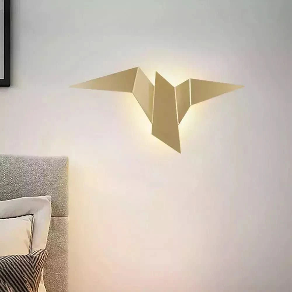 Applique murale dorée fixée près d'un lit avec tête de lit capitonnée et coussins.