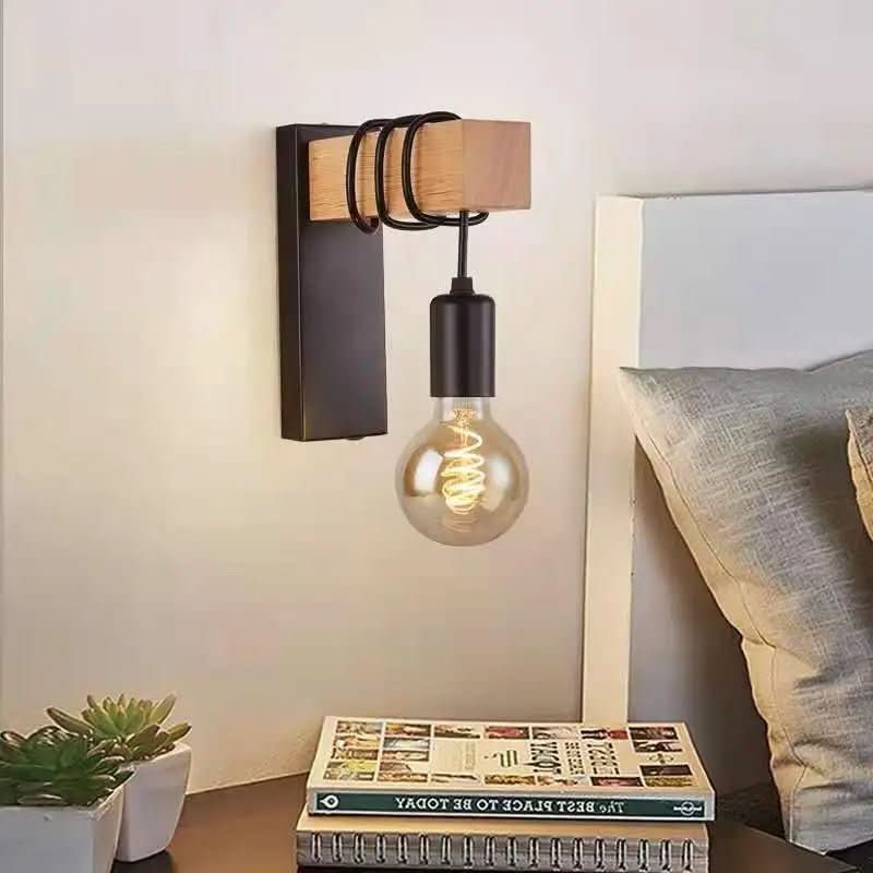 Applique murale fixée au-dessus d'une table de chevet avec livres et plante grasse.