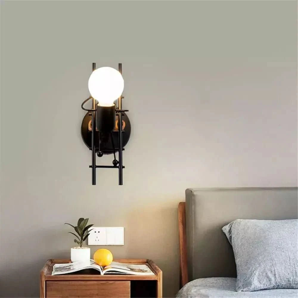 Mise en scène chambre : applique noire allumée au-dessus d'une table de chevet en bois.