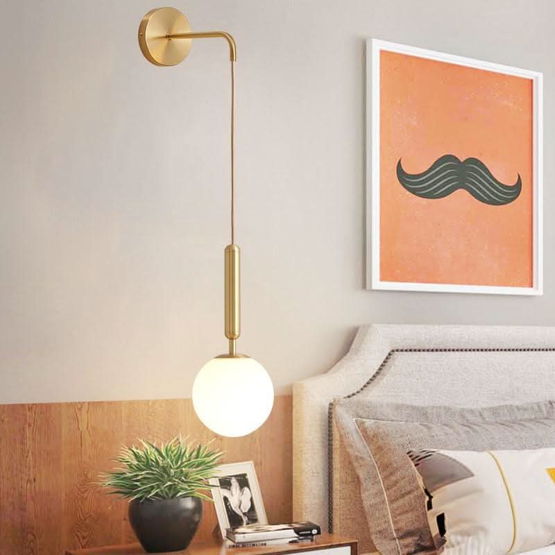 Mise en ambiance chambre avec applique dorée allumée au-dessus d'une table de chevet en bois