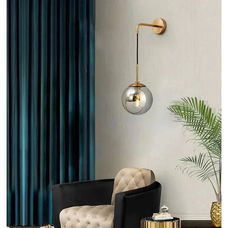 Mise en ambiance salon : applique suspendue devant rideaux bleus, fauteuil et plante.