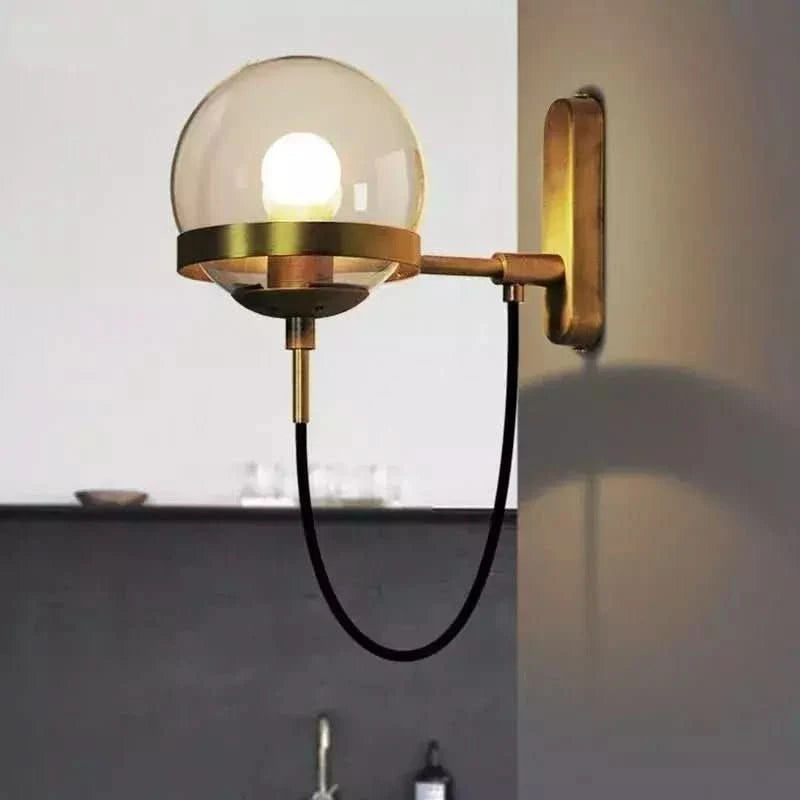 Vue de face du globe en verre clair monté sur bras métallique doré fixé au mur