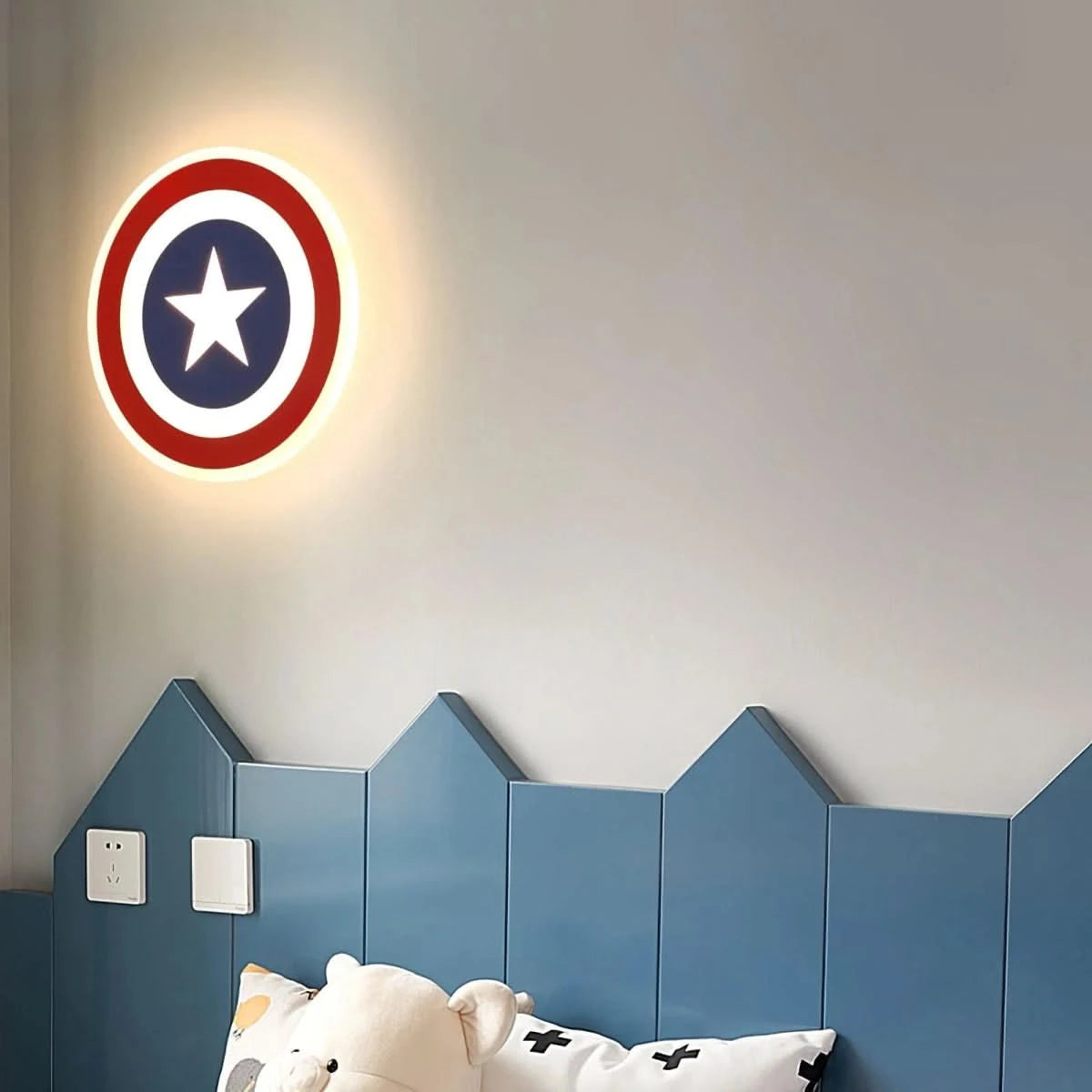 Ambiance chambre enfant, applique éclairée sur mur blanc près d'une tête de lit bleue