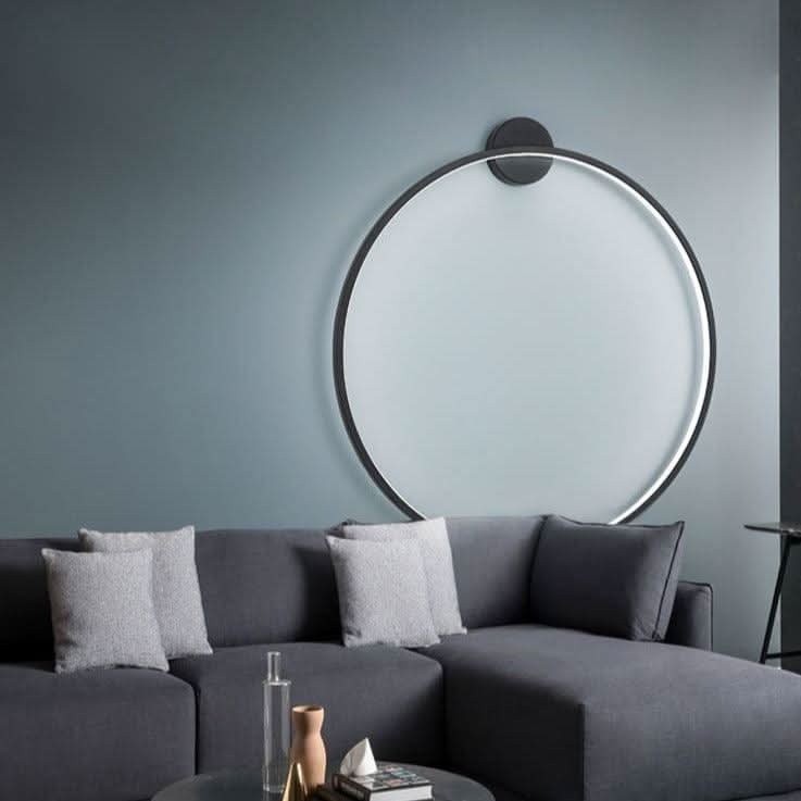Applique ronde noire installée sur mur bleu-gris au-dessus d'un canapé d'angle