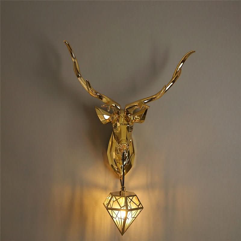 Applique murale dorée seule sur mur beige, lumière chaude diffusée par le losange.