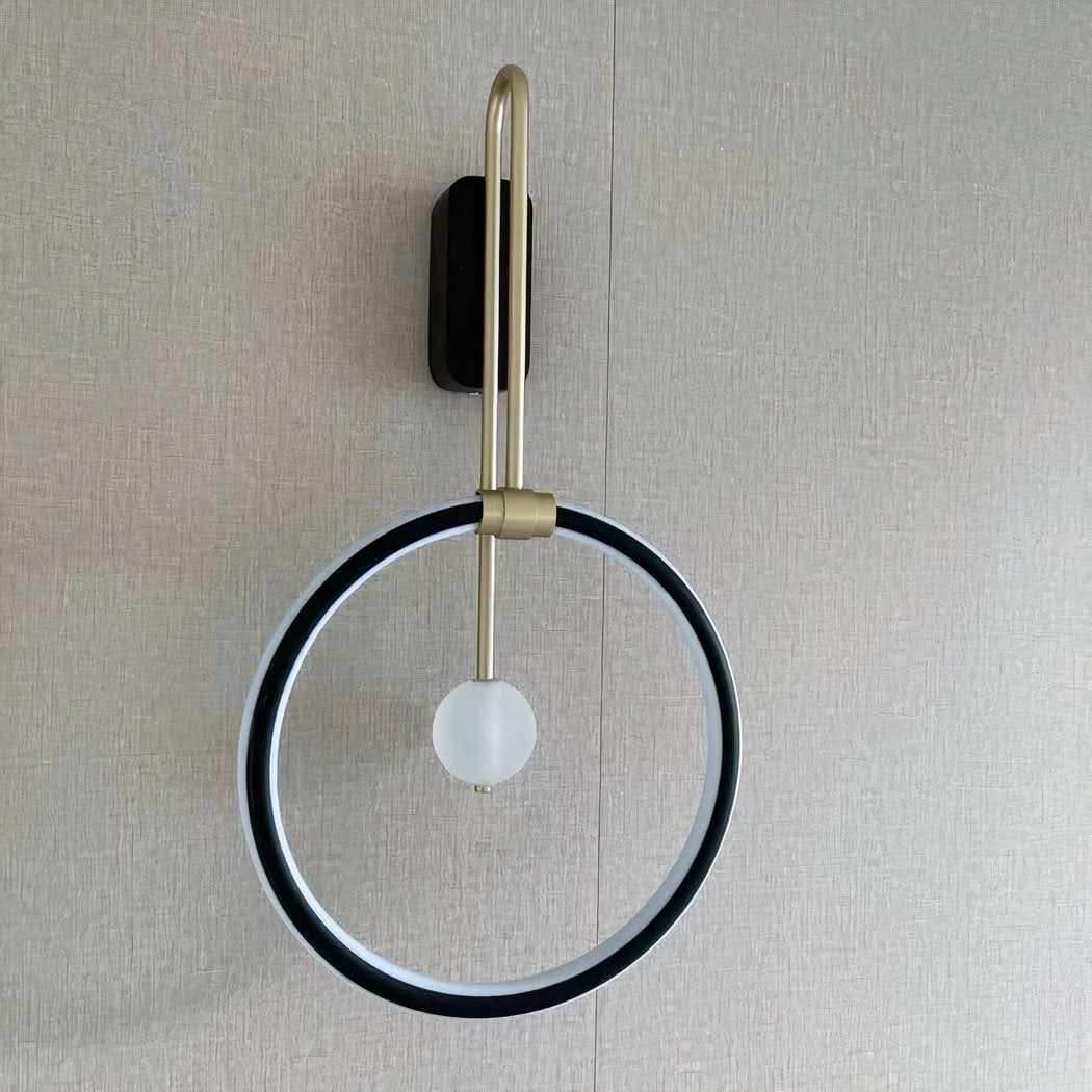 Produit de face sur un mur gris, anneau noir et globe central en verre.