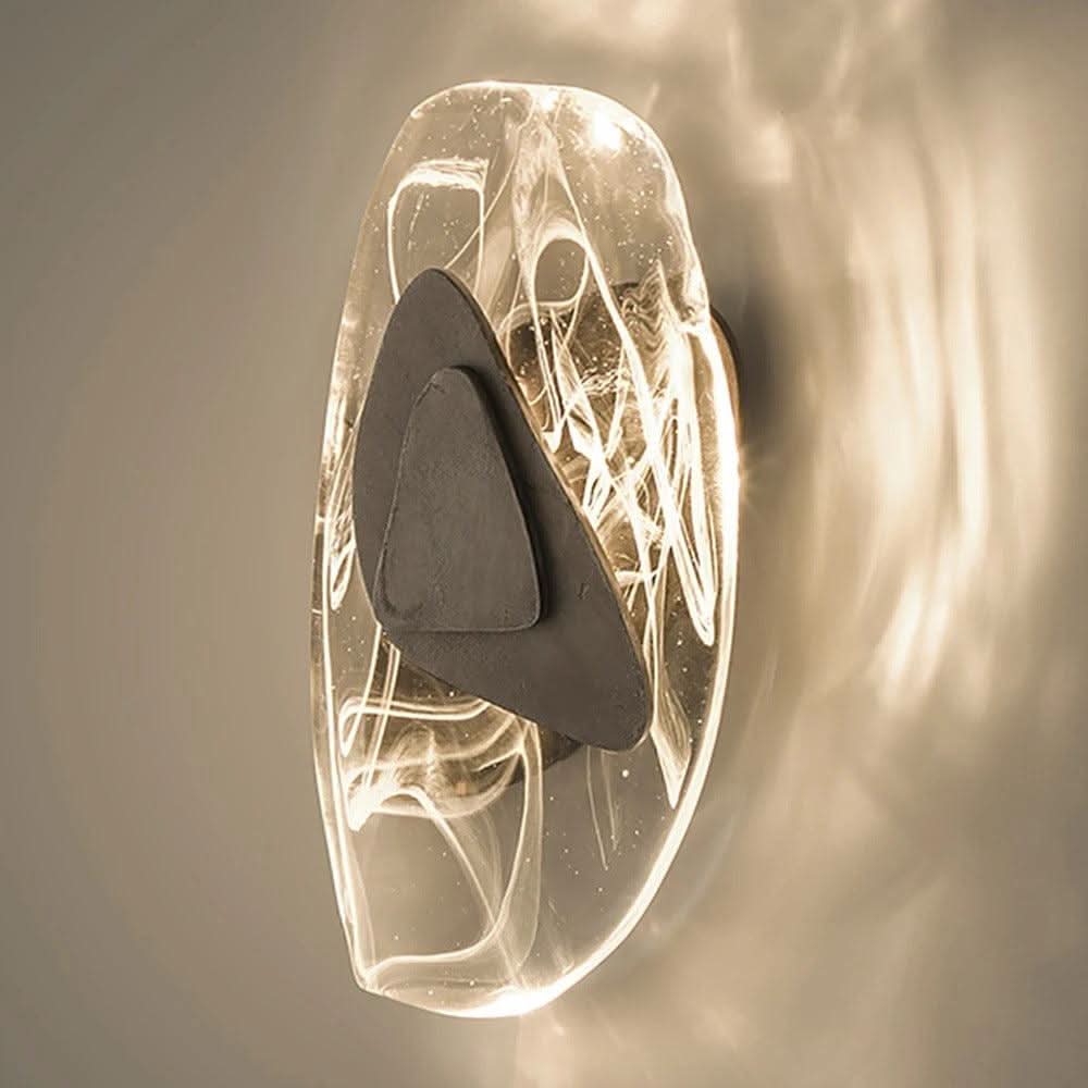 Vue rapprochée de face du luminaire, verre transparent et plaque métallique sombre au centre.