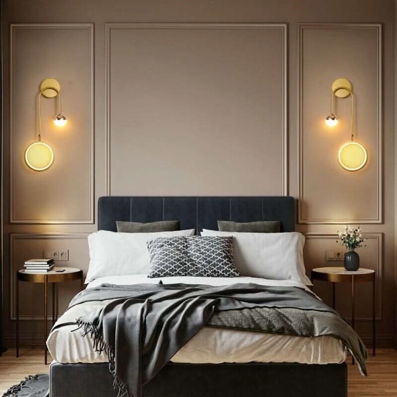 Chambre avec deux appliques murales dorées de part et d'autre du lit.