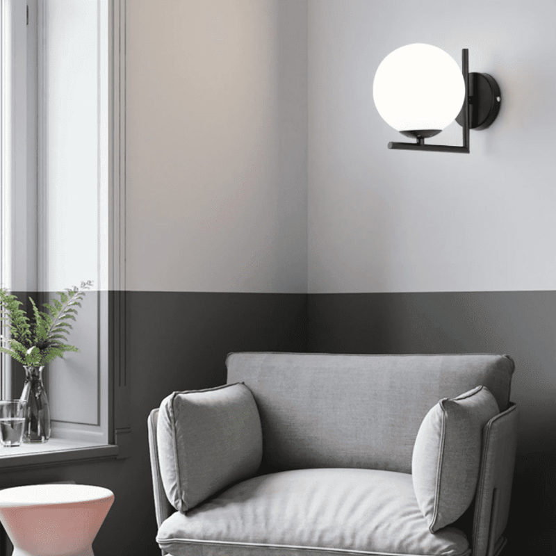 Ambiance intérieure grise, applique noire éclairée près d'une fenêtre et d'un fauteuil