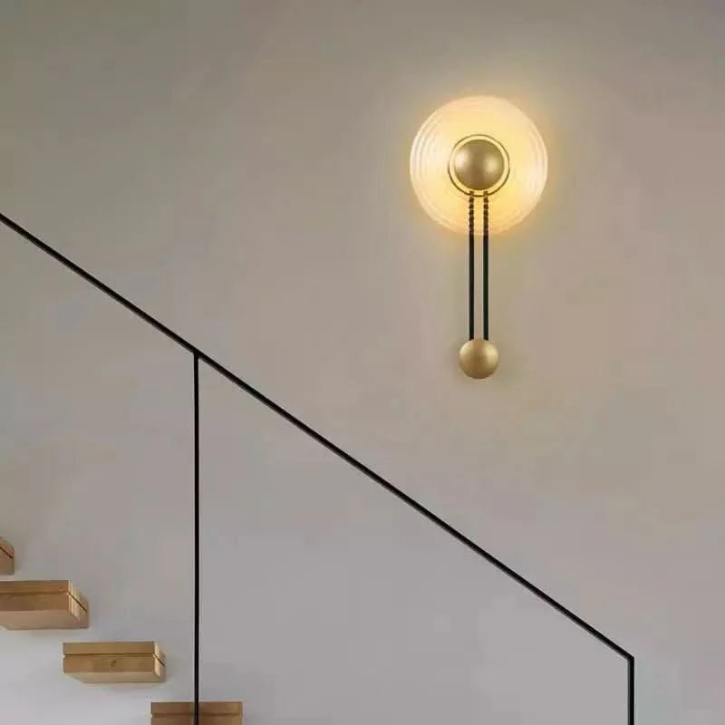 Applique allumée éclairant un mur blanc près d'un escalier en bois