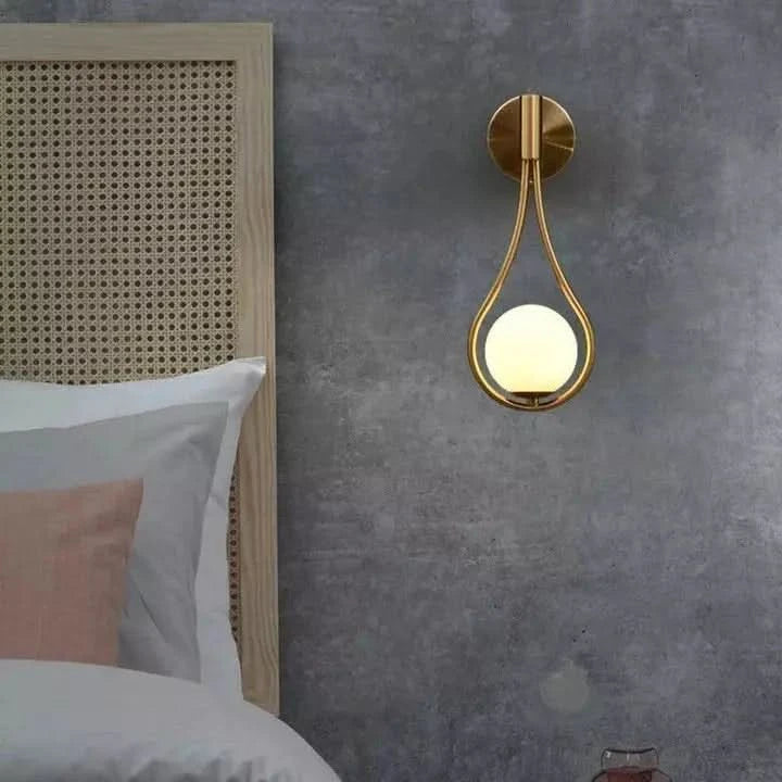 Applique dorée sur mur gris béton, tête de lit en cannage et linge blanc