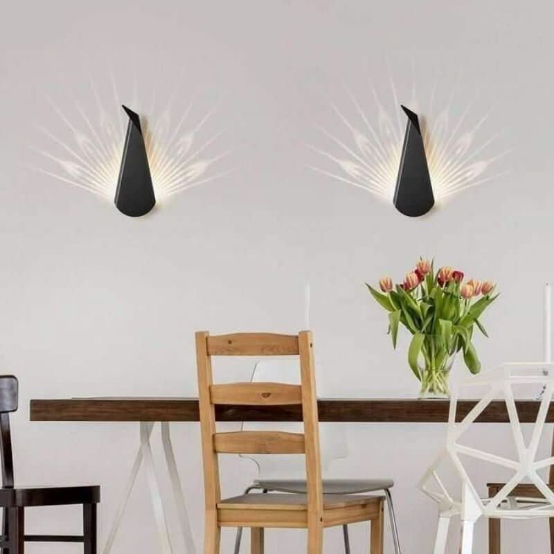 Deux appliques murales noires allumées au-dessus d'une table en bois, vase de tulipes.