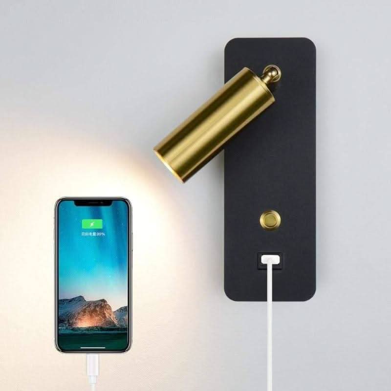 Détail de la prise USB intégrée, smartphone branché et éclairé sous l'applique murale.