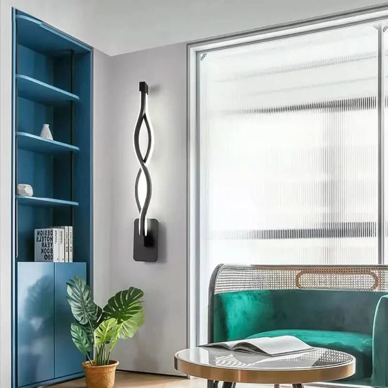 Applique noire ondulée sur mur gris, bibliothèque bleue et canapé vert en arrière-plan