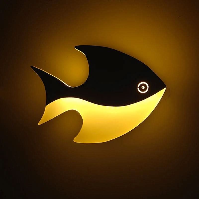 Vue de face du luminaire poisson diffusant une lumière dorée sur fond sombre.
