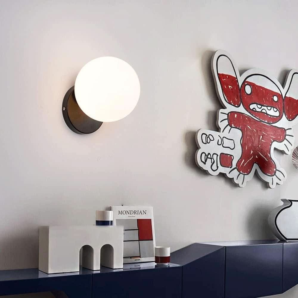 Applique noire à globe blanc lumineux, mur gris, décoration colorée et revue sur meuble