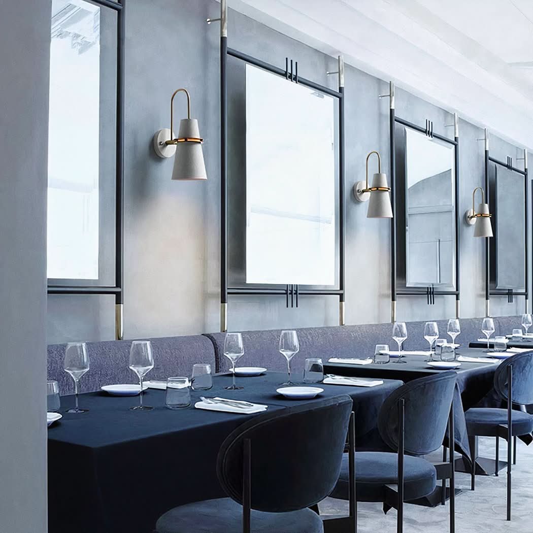 Plusieurs appliques beiges alignées au-dessus de tables de restaurant et grands miroirs.