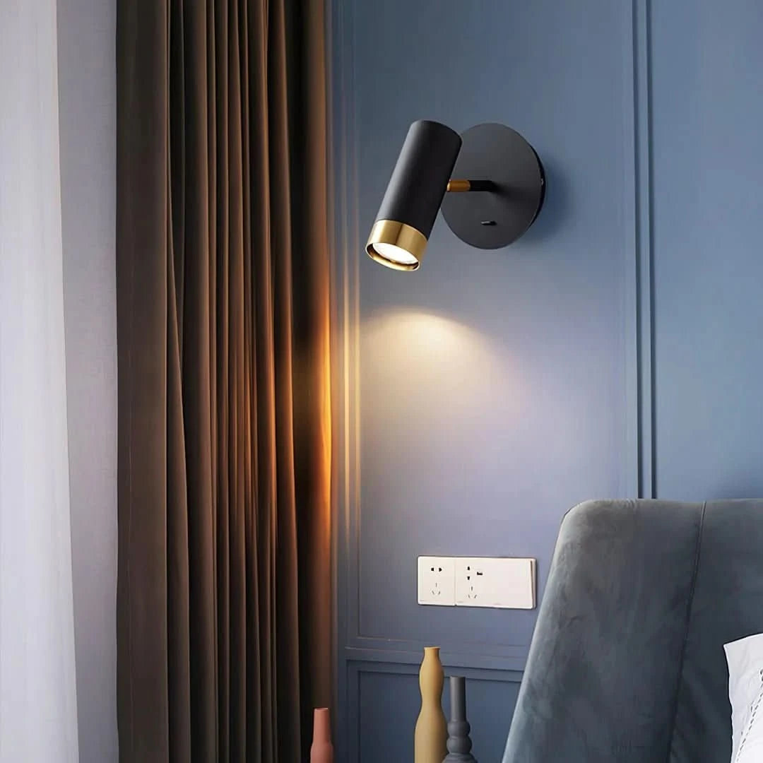 Ambiance mur bleu nuit, applique noire et dorée projetant un halo chaud