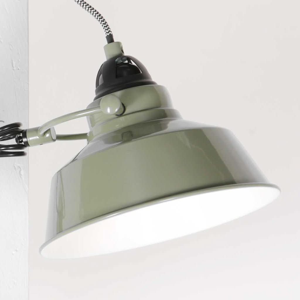 Détail rapproché de l'abat-jour vert brillant, douille noire et intérieur blanc.