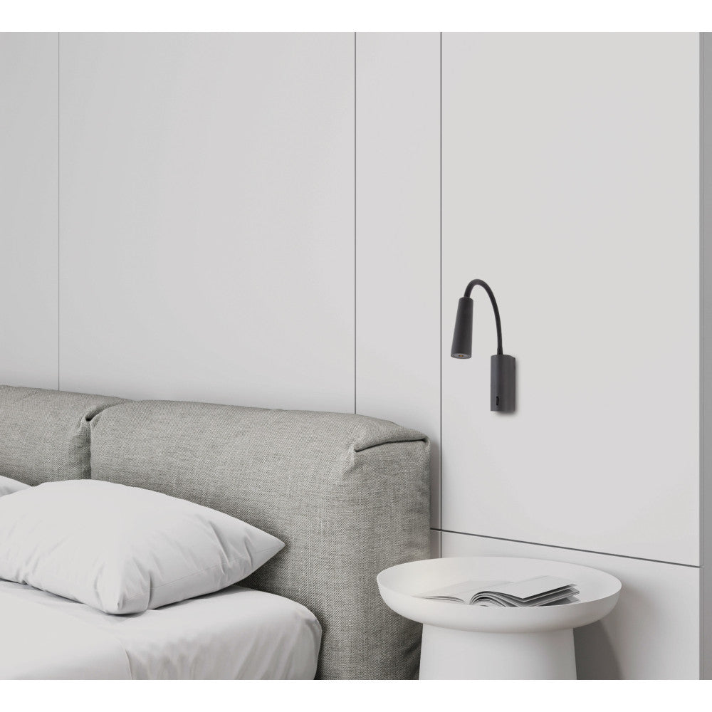 Mise en ambiance près d un lit, applique murale noire orientable au-dessus d une table de chevet.