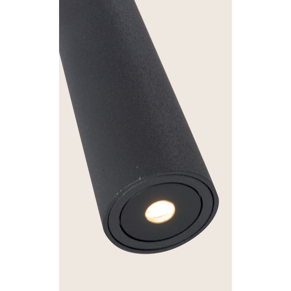 Détail rapproché de la tête cylindrique allumée, finition noire texturée et diffuseur LED.