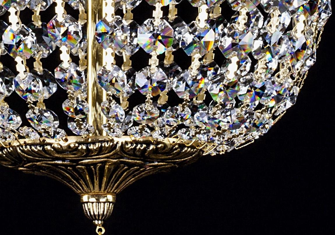 Gros plan du bas du luminaire, tige centrale dorée et rosaces de cristal