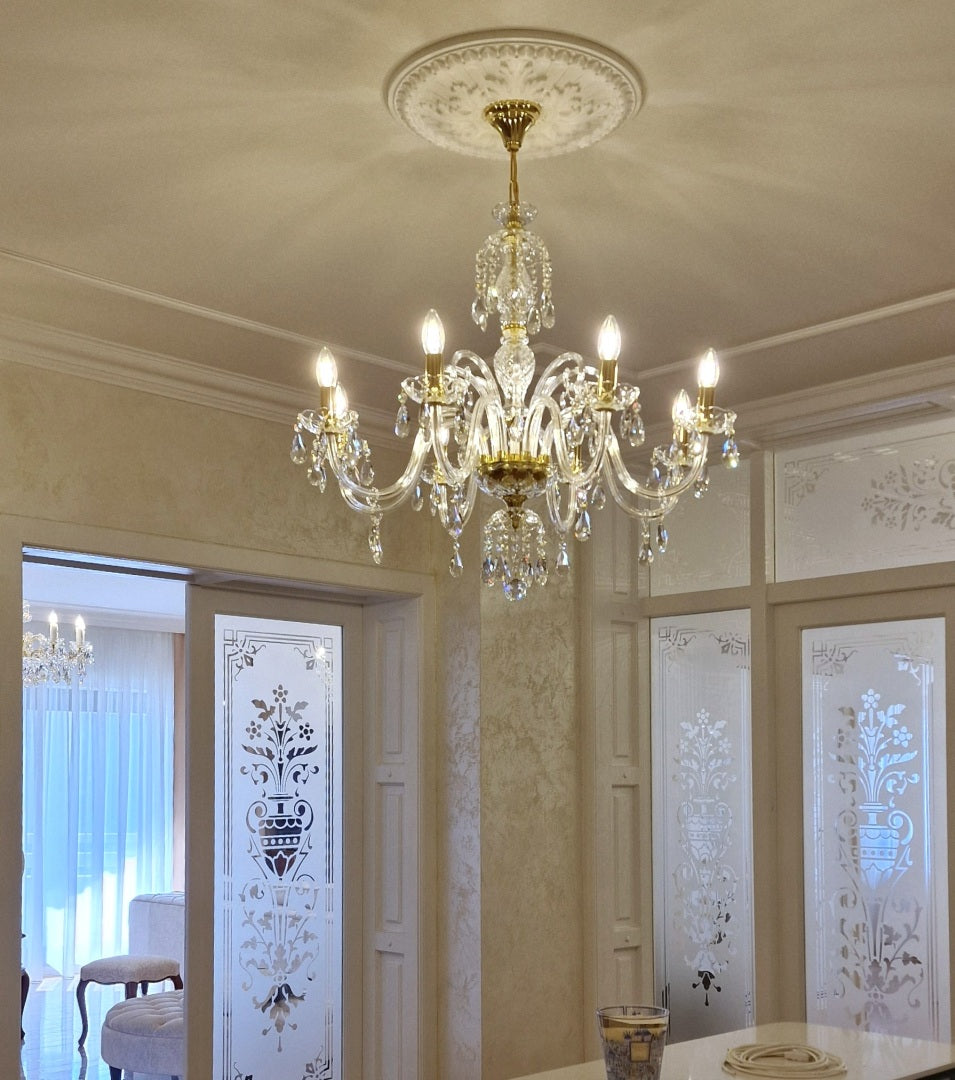 Lustre suspendu au plafond dans une pièce moulurée, éclairage allumé et décor floral