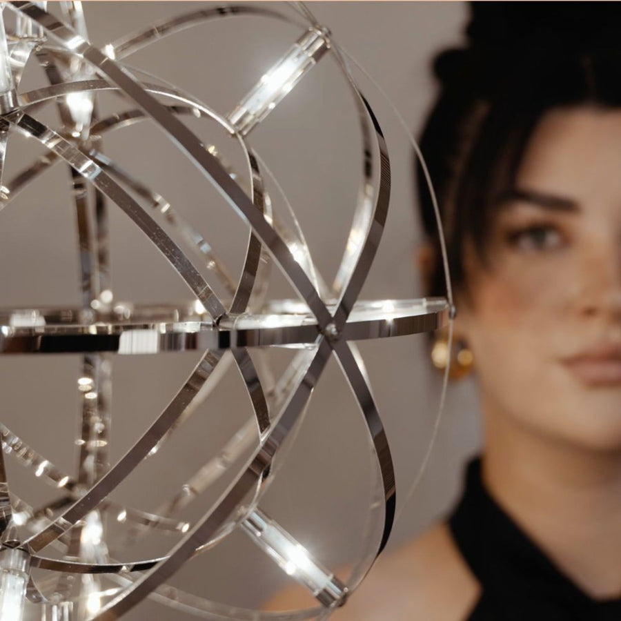 Détail d'un globe cage chromé aux bandes métalliques entrelacées et LED allumées.