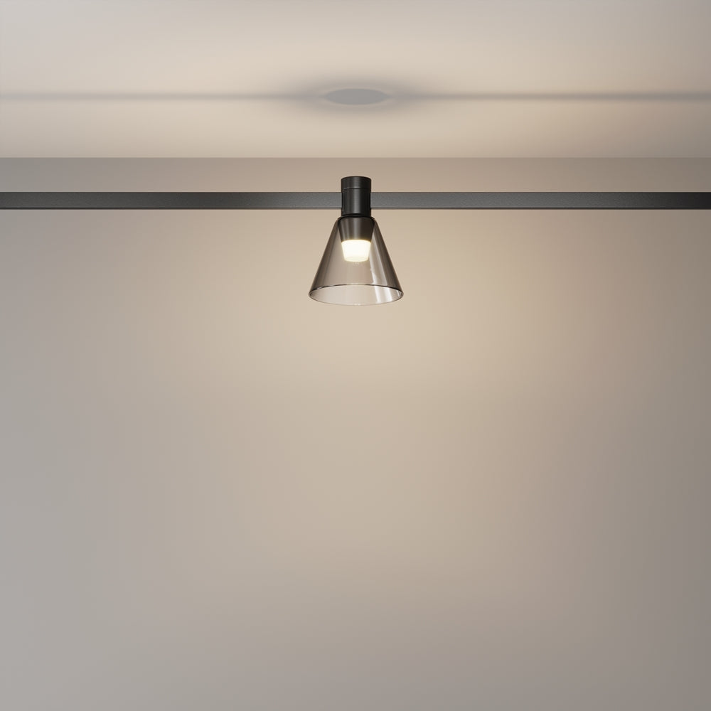 Spot allumé sur rail, halo lumineux diffusé sur le mur clair