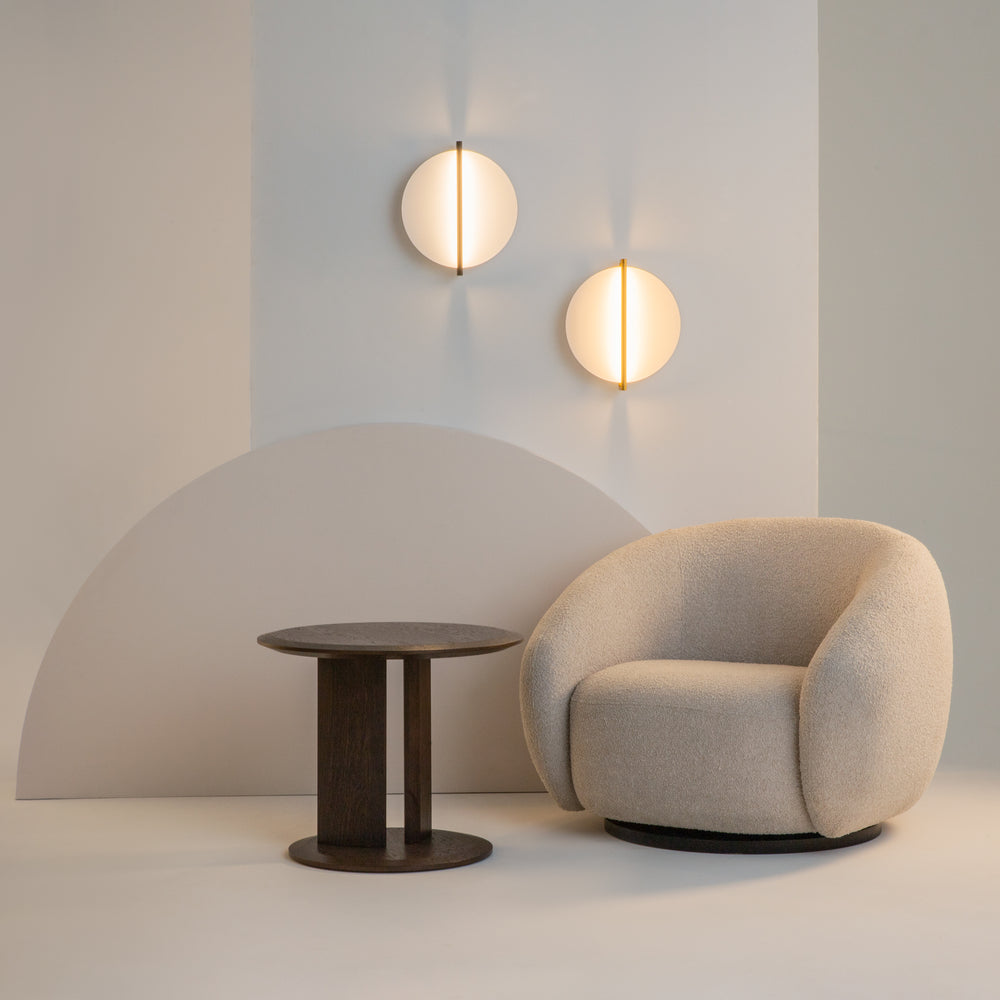 Mise en ambiance avec deux appliques allumées au-dessus fauteuil et table basse