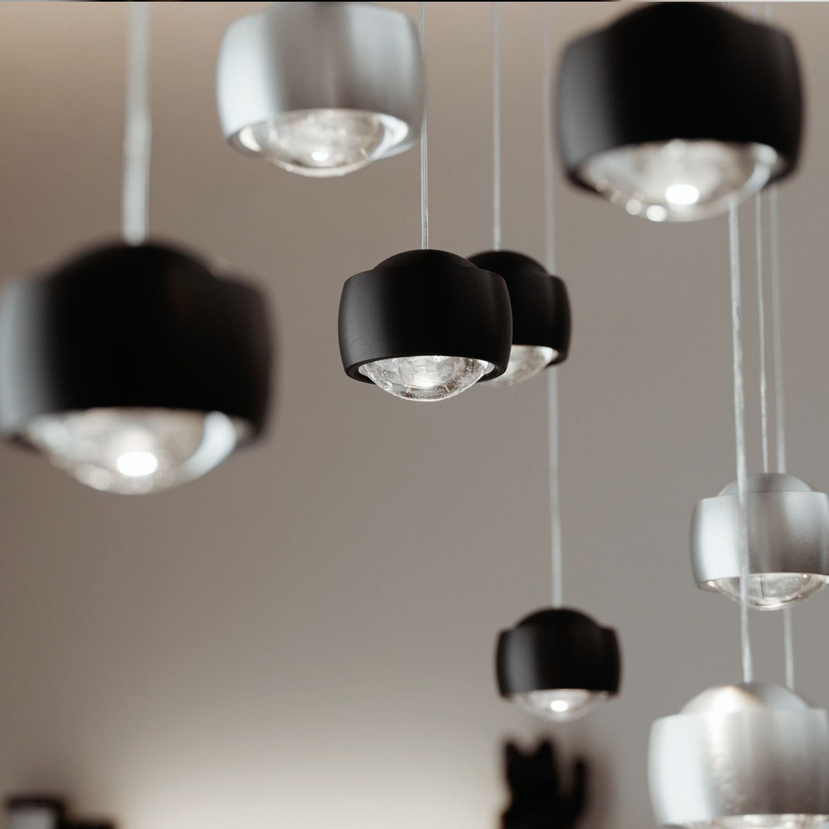 Gros plan sur les têtes de suspension noires et argentées avec diffuseurs en verre.