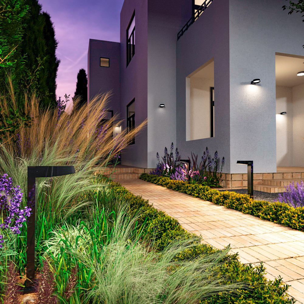 Mise en ambiance nocturne de bornes noires éclairant une allée de jardin