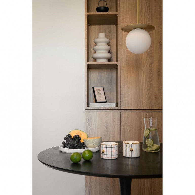Mise en ambiance avec un pendant doré devant une niche en bois et une table.