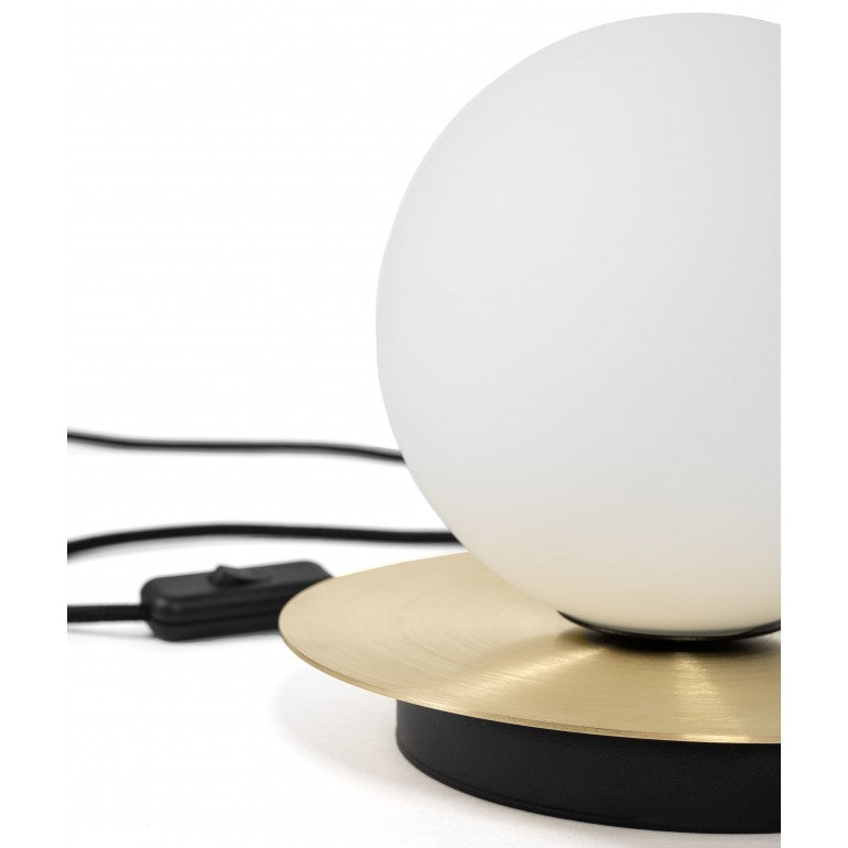 Détail du socle en laiton brossé, du globe et de l'interrupteur noir sur câble.