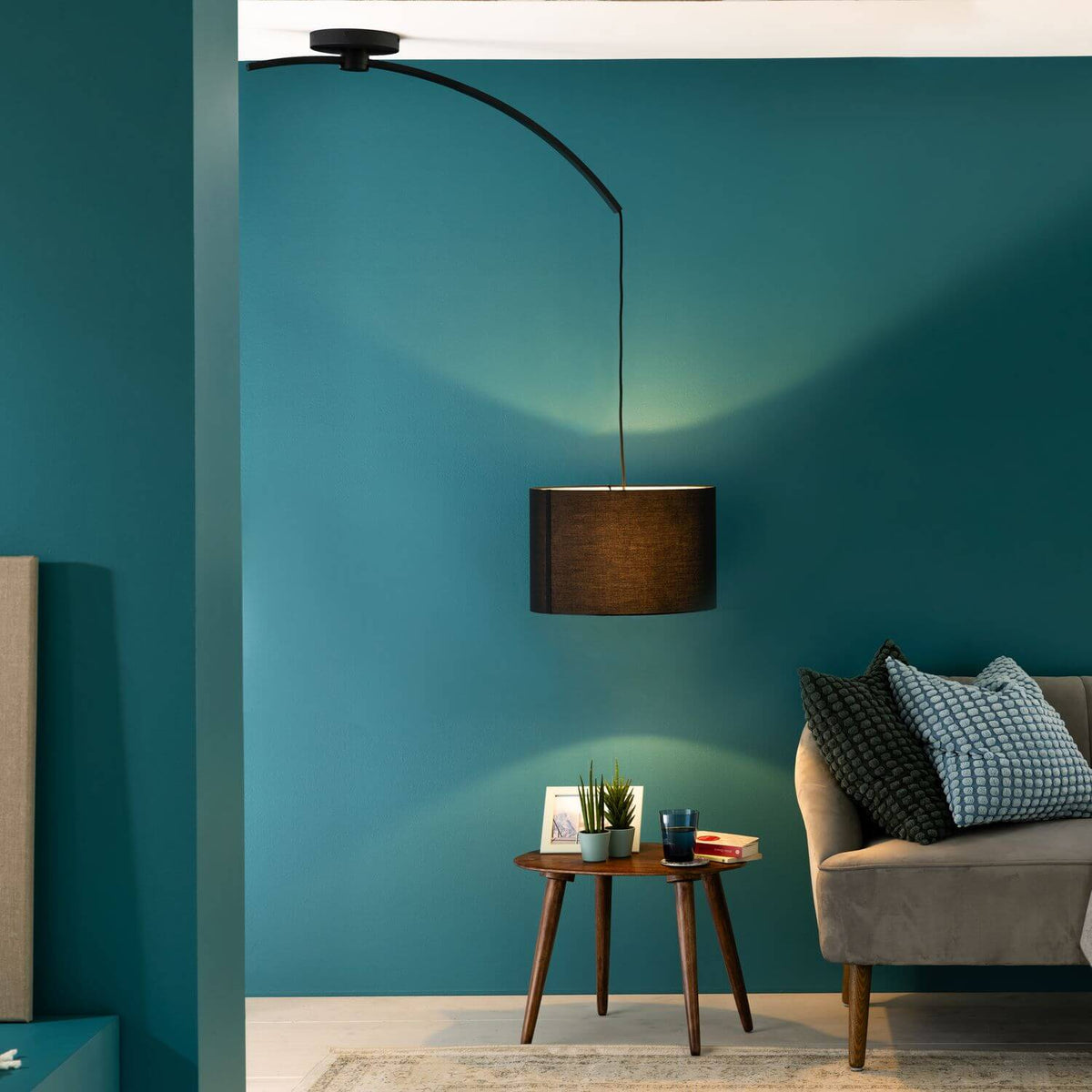 Mise en ambiance, suspension allumée au-dessus d'une table basse devant un mur bleu